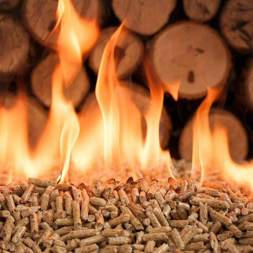 Brennende Pellets vor einem Holzstapel